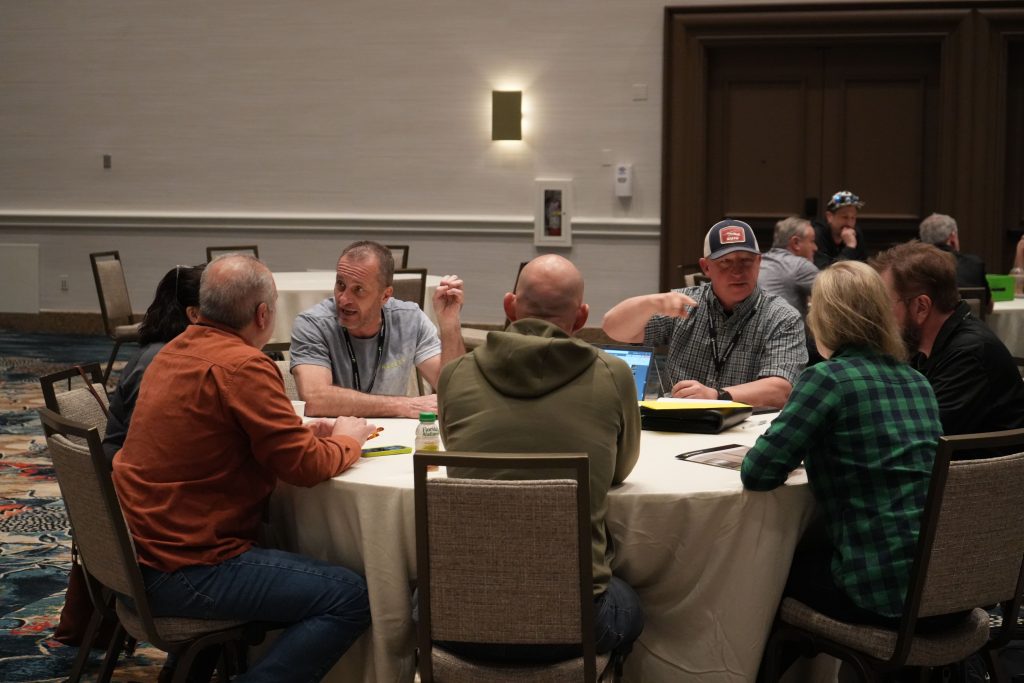 Group of people sitting around a table engaged in discussion in a conference room setting.